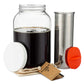 Rumble Jar one gallon 128 ounce cold brew coffee filter with orangey-red cap cotton filter sock and hangtag next to a glass jar containing coffee