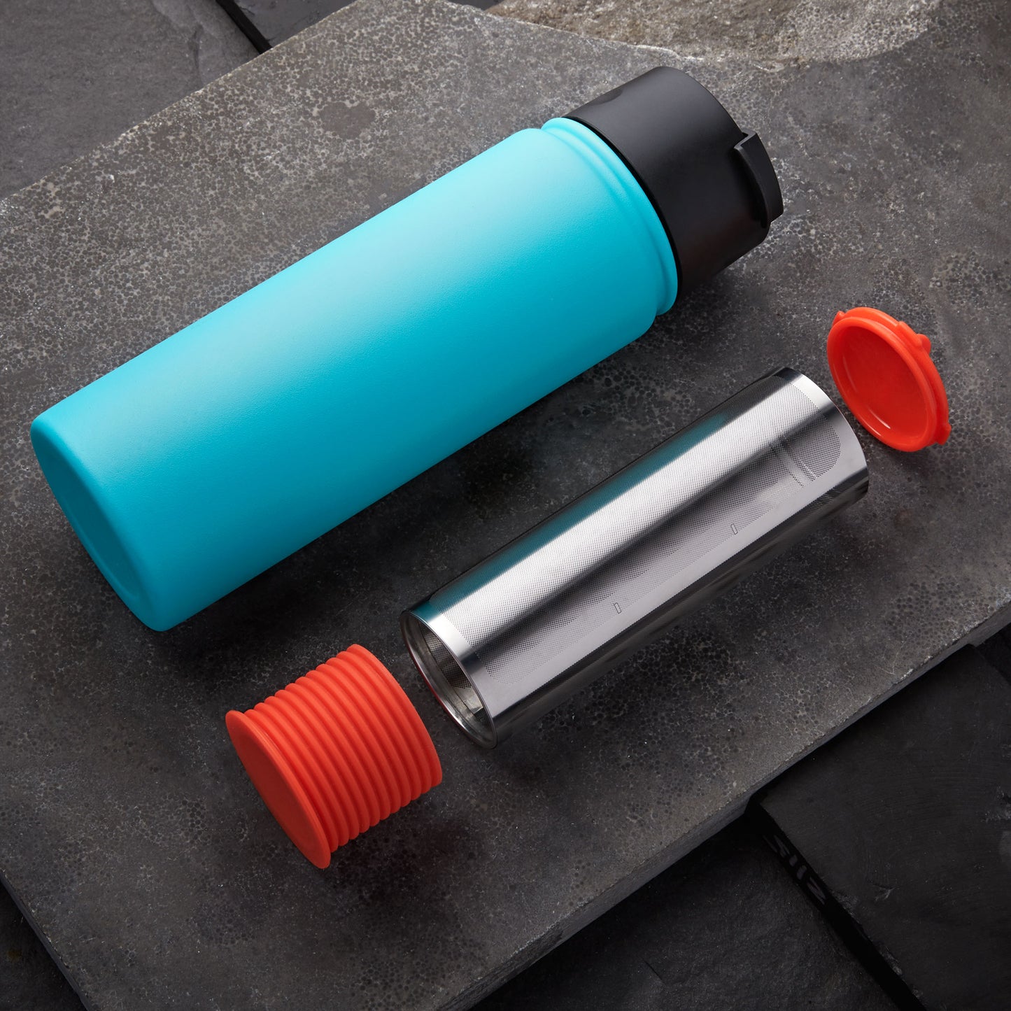 Rumble Go cold brew coffee filter with orangey-red cap and base next to one of many compatible water bottles